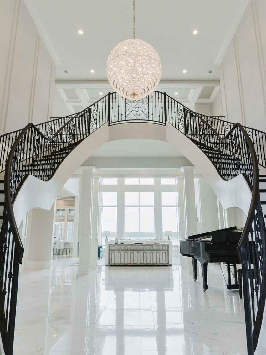 A beautiful coastal home interior featuring a large wrap-around staircase with black iron handrail.