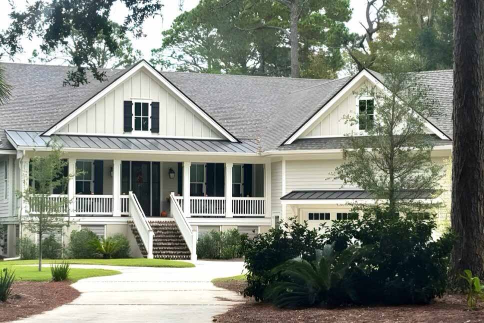 A charming light-colored house with a gable roof, front porch, and white railings.