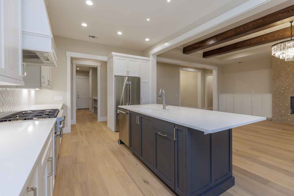 Spacious kitchen with a sleek black island, white countertops, and cabinets. Large windows provide natural light.