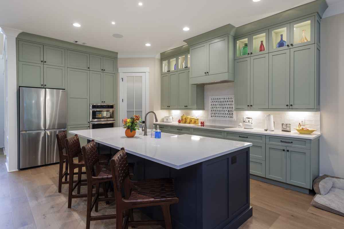 Photo of a kitchen island featuring a light colored marble top against pale green kitchen cabnetry.